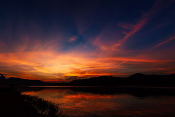 Sunrise time at lake or river with mountain on the background. in dark tone.
