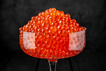 Red caviar in a crystal bowl on a black background. Delicacy product of the highest quality.