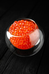 Red caviar in a crystal bowl on a black background. Delicacy product of the highest quality.