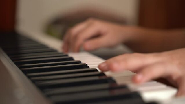 The girl is learning to play the electronic piano at home. Close-up