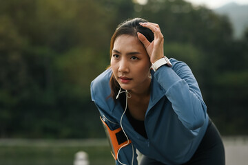 Naklejka premium Tired sportswoman wiping sweat, taking a break after running outdoors. Fitness, sport and healthy lifestyle concept