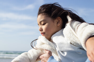 Happy little girl in white coat on beach. Japanese child on beach on summer day. Childhood,...