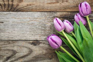Bouquet of purple tulips on a wooden surface, fresh spring flowers, top view, copy space.