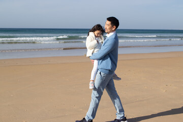 Happy father and daughter spending time on beach. Japanese family walking, hugging, dad carrying little girl. leisure, family time, parenting concept