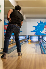  Young man playing bowling in the game area, young man throwing rolling bowling ball to target