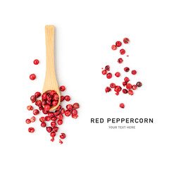 Red peppercorns in bamboo spoon on white.