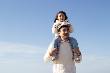 Happy Japanese family together on sunny day. Father and daughter playing, riding on shoulders. Leisure, family time, parenting concept