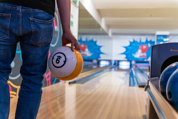 Young asian holding bowling ball, relaxing concept, a man's hand throws a bowling ball close-up, a...