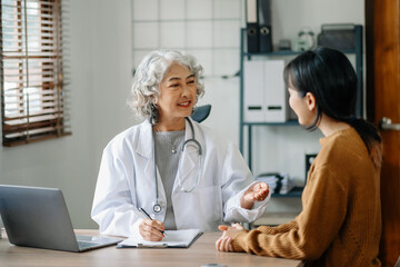 Obraz premium Asian Doctor and patient discussing something while sitting at the table . Medicine and health care
