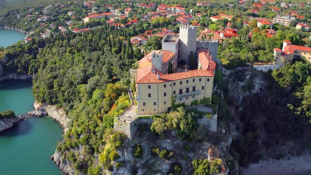 4k drone flight up footage (Ultra High Definition) of Duino Castle on the edge of high cliff. Green  summer scene of Adriatic coast of Italy, Europe. Exciting morning cityscape of Duino town.