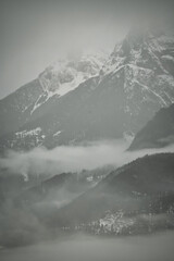 Dreamy mysterious winter landscape with fog and snow covered mountains and trees