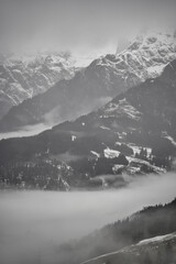 Obraz premium Dreamy mysterious winter landscape with fog and snow covered mountains and trees