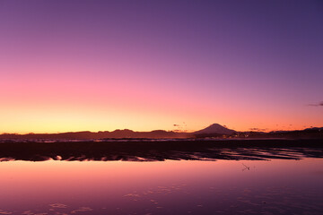 Fototapeta na wymiar 砂浜にできた水鏡と夕焼けと富士山