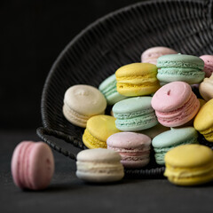 Macaroni. French dessert. Colorful macaroni in wicker basket. Basket of dark vines. Dark background.