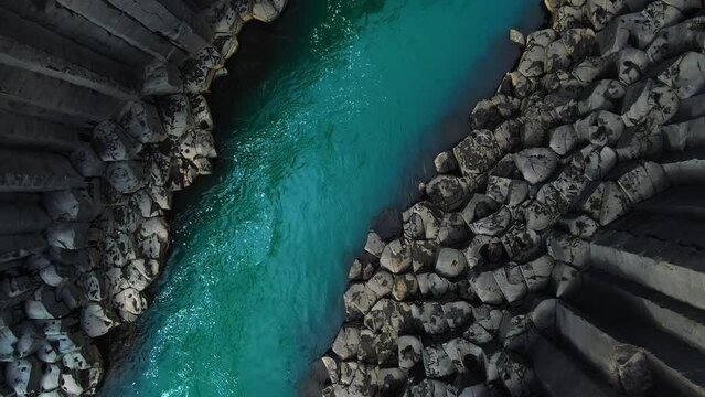 top down view aerial shot drone of studlagil canyon,river water flowing into basaltic rock formation,iceland nature
