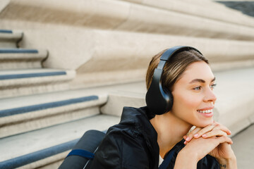 Young woman listening to music while sitting on stairs after workout