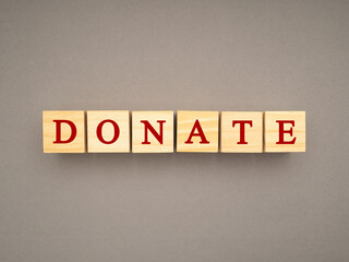 Obraz premium Top view of wooden cubes with the letters DONATE on a gray background