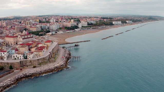 4k drone flight back footage (Ultra High Definition) of Termoli port. Calm morning cityscape of Sant'Antonio beach. Splendid sunrise on Adriatic sea. Traveling concept background.