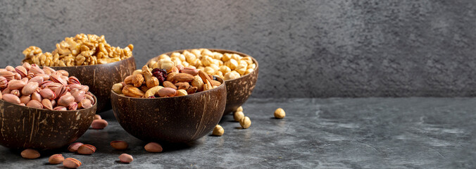 Walnuts, pistachios, hazelnuts and mixed nuts in a bowl on a dark background. Empty space for text. copy space