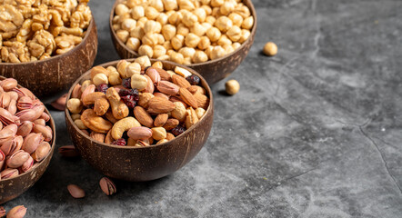 Walnuts, pistachios, hazelnuts and mixed nuts in a bowl on a dark background. Empty space for text. copy space