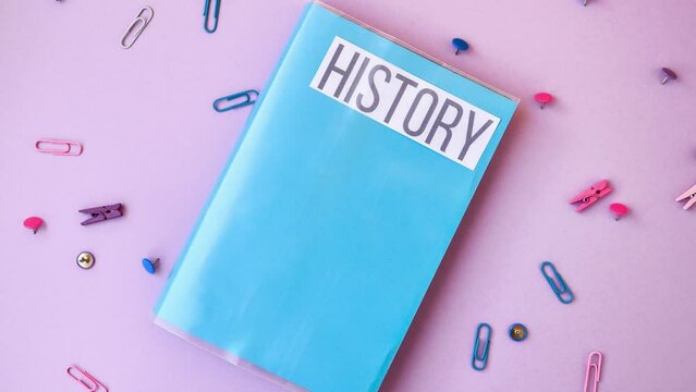 4k zoom in out school book. history with supplies stationery on color background, back to school, ruler, pencils