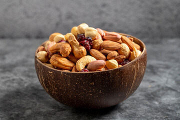 Naklejka na ściany i meble Mixed nuts in bowl on dark background. Nuts, cashews, almonds and pistachios in a coconut bowl. close up