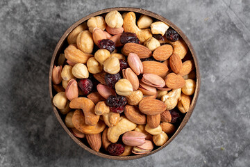 Mixed nuts in bowl on dark background. Nuts, cashews, almonds and pistachios in a coconut bowl. Top view