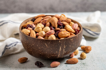 Mixed nuts in bowl on gray background. Nuts, cashews, almonds and pistachios in a coconut bowl. close up