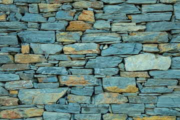 wall of mixed gray and assorted-colored rocks texture background.