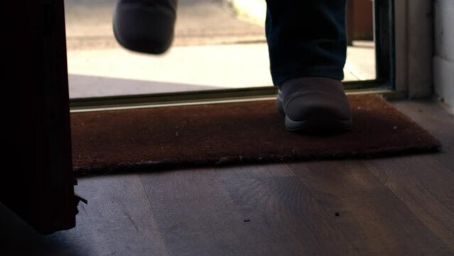 Wiping feet on welcome mat in door entrance 