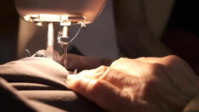 Hands-working sewing machine in motion. close-up of sewing machine needle quickly moves up and down. Old woman working. The process of sewing the fabric.