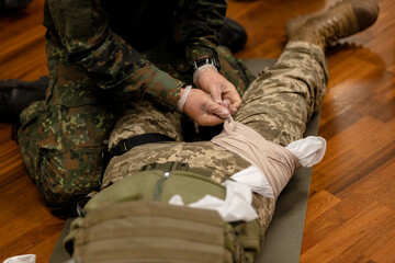  Training dressing of the wounded leg of a Ukrainian fighter, close-up. View from above