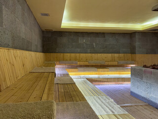 Seat in sauna room. Empty wooden steam room with stone heater.Sauna room for good health. Sauna...
