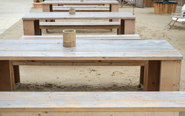 Nahaufnahme Bank und Tisch in einem großen Beachclub mit Sand, Dekoration und weiterem Mobiliar im...