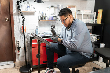 A tattoo artist is putting on latex gloves before tattooing in his work studio station
