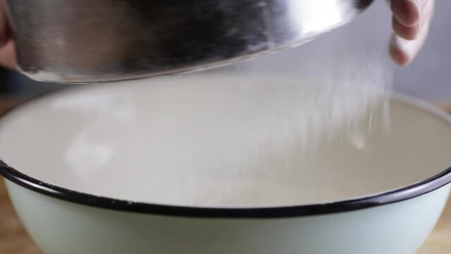 The cook is sifting flour through a sieve.
