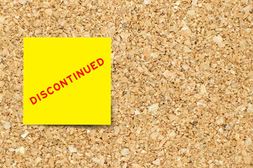 Yellow note paper with word discontinued on cork board background with copy space