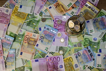 Coins in a glass jar and Euro banknotes bills on the table. The concept of investment, interest.Coins in a glass jar and large Russian bills on the table. The concept of investment, interest.