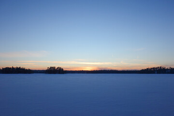 Sunset over the snowy frozen lake 