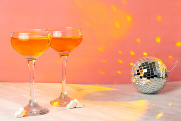 Orange cocktail with tall glasses on a pink background. Two glasses