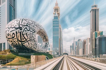 Rolgordijnen Metro railway among among glass skyscrapers in Dubai. Traffic on street in Dubai. Museum of the Future in Dubai. Cityscape skyline. Urban background. © Grigory Bruev