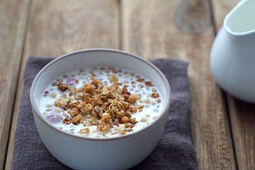 A plate of muesli stands on a wooden table. Selective focus