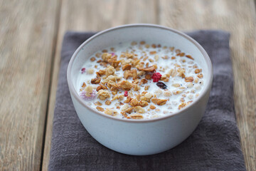 A plate of muesli with raspberries and raisins stands on a wooden table. Selective focus
