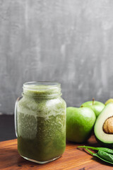 Green smoothie drink blended in a glass jar, avocado, spinach leaves and apples at wooden board