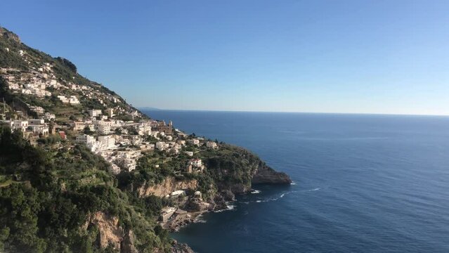 Panoramic view of beautiful Amalfi on hills leading down to coast, Campania, Italy. aerial skyline of small haven of village with tiny beach and colorful houses, located on rock and mountains