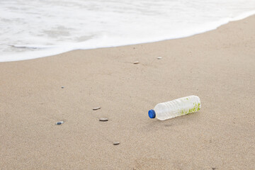Empty used dirty plastic bottle on the sea beach of a big city. Environmental pollution. Ecological concept. Earth day concept. Globe pollution. Garbage on beach.