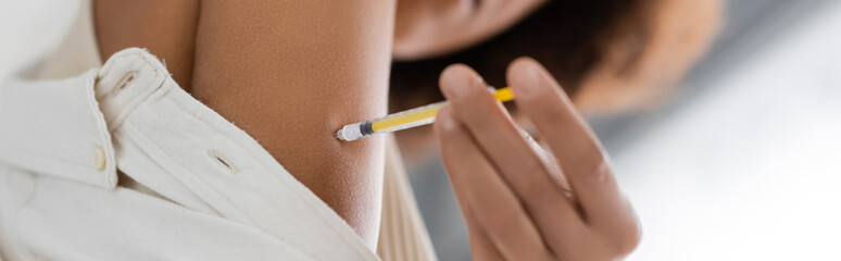 Low angle view of blurred african american woman with diabetes doing injection of insulin, banner