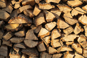 Stacked pile of firewood as a background. Firewood chopped for burning in a stove or fireplace. Woodpile in the rays of the winter sun. Place for text.