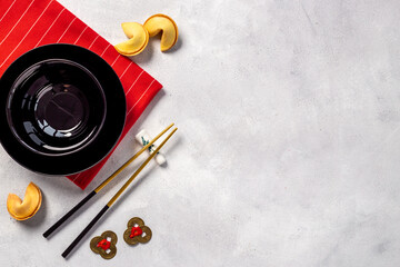 Fototapeta na wymiar Golden chopsticks on black bowl with red napkin. Asian tabble place setting