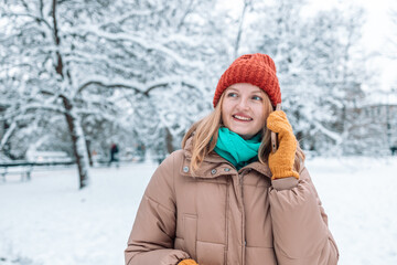 Fototapeta na wymiar Portrait of young beautiful woman having mobile phone conversation in her smartphone. Festive Christmas. Magic snowfall effect. 